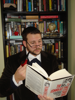 Adam Floridia reading a book and holding a pipe