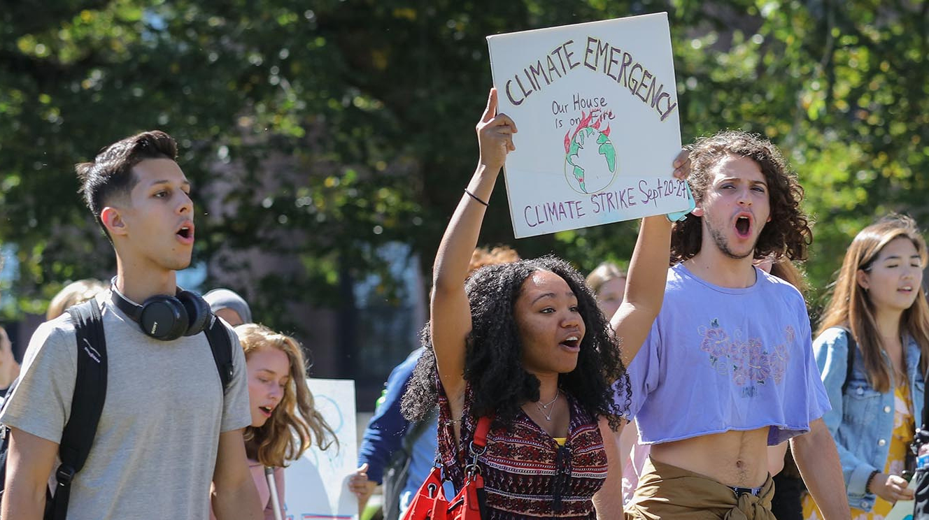 students march and hold up climate emergency signs in protest