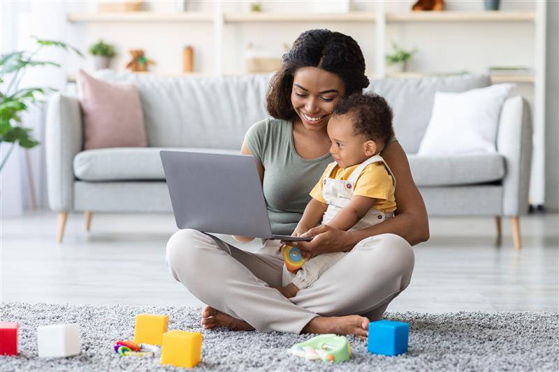 mother with baby looking at laptop happily