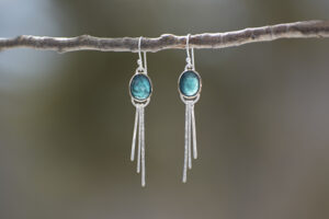 teal droop earring hanging from branch