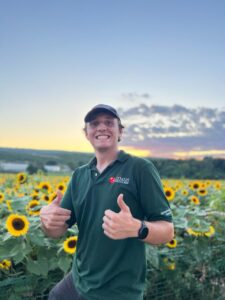 Max with thumbs up in sunflower field during sunset