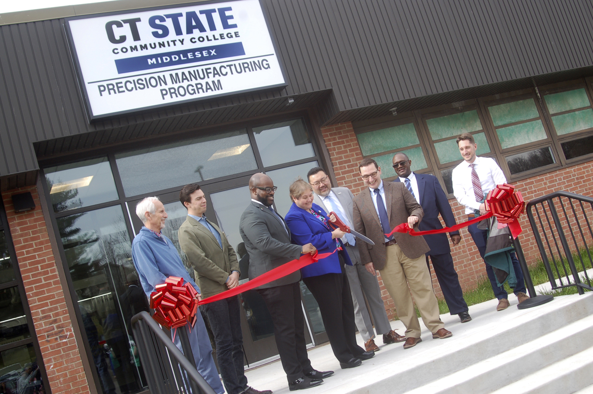 group cutting ribbon in front of manufacturing lab entrance